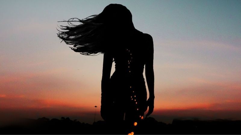 Silhouette woman at sunset, flowing hair, HD quality, 450x800 resolution, captivating evening sky background.
