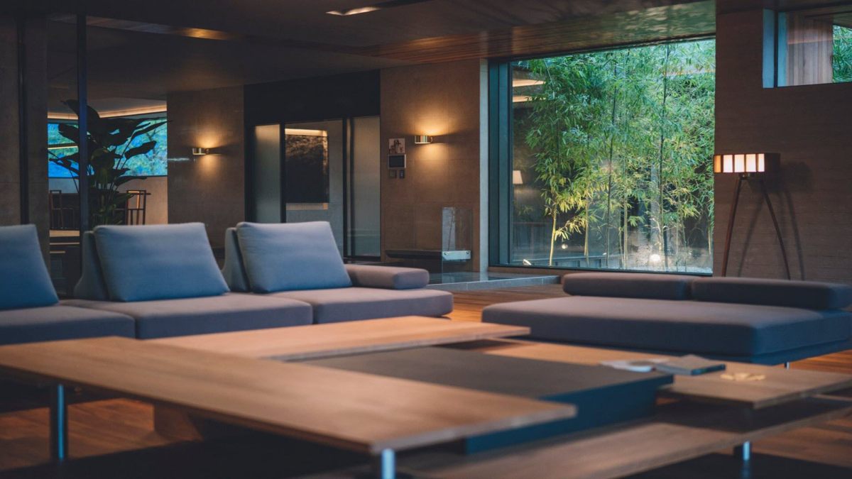 Phong cách nội thất hiện đại với ghế sofa xanh trong phòng khách, cửa kính hướng ra vườn cây, chất lượng HD 1080x1920.